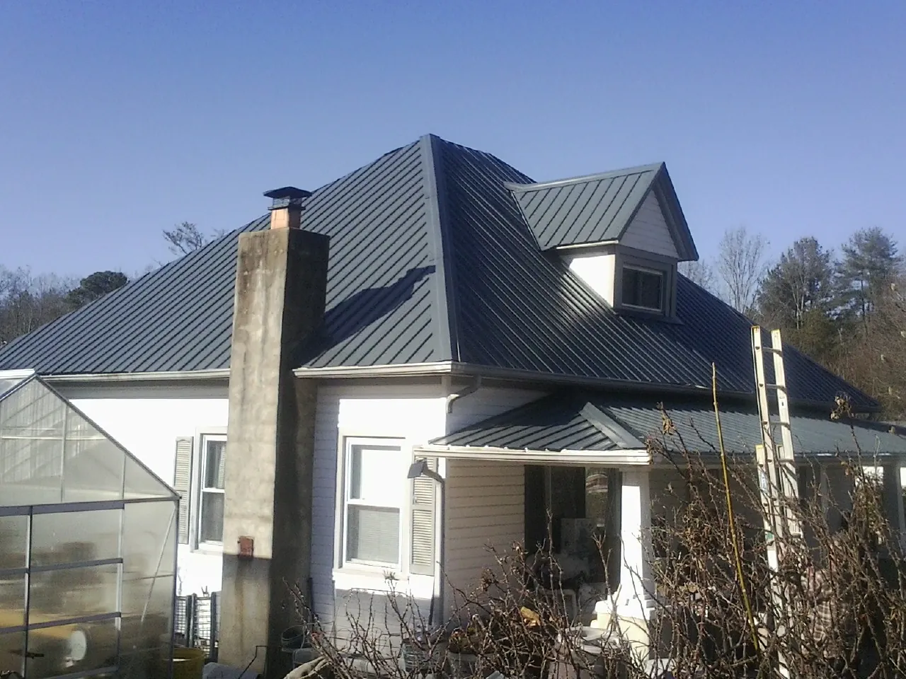 Dark blue standing seam metal roof on a white farmhouse with dormer — Slate & Tile Roof Repair by Roofing Brothers in Mifflinburg