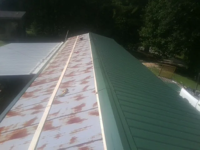 Old rusted panels beside newly installed green metal roofing — Wind Damage Roof Repair by Roofing Brothers in Mifflinburg