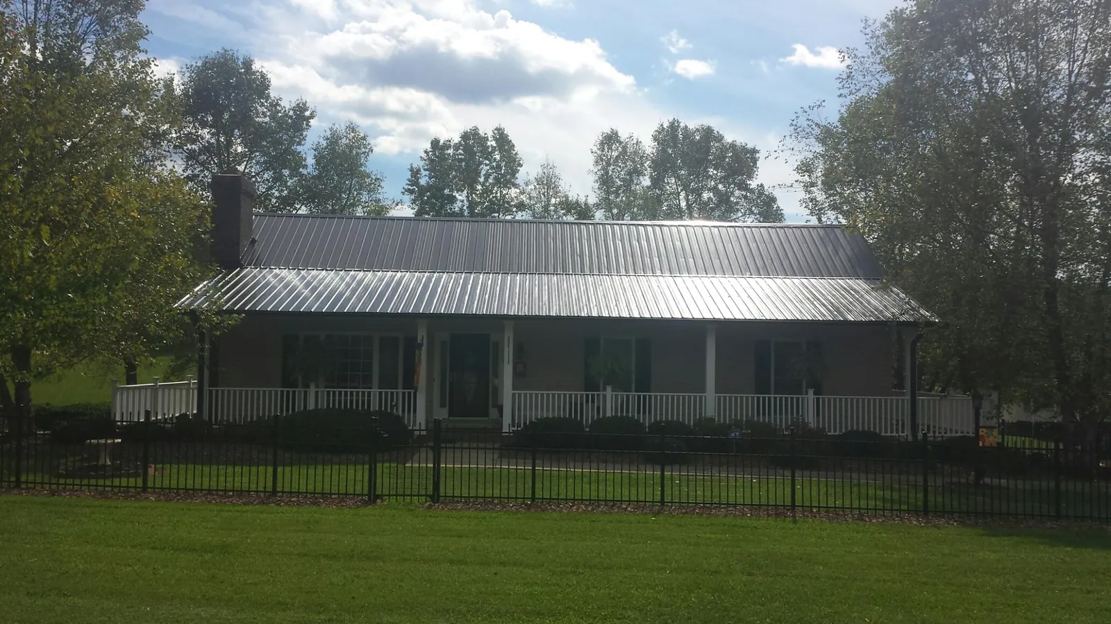 Gray metal roof on a brick ranch with a full width front porch — Gutter Guard Installation work by our crew in Mifflinburg