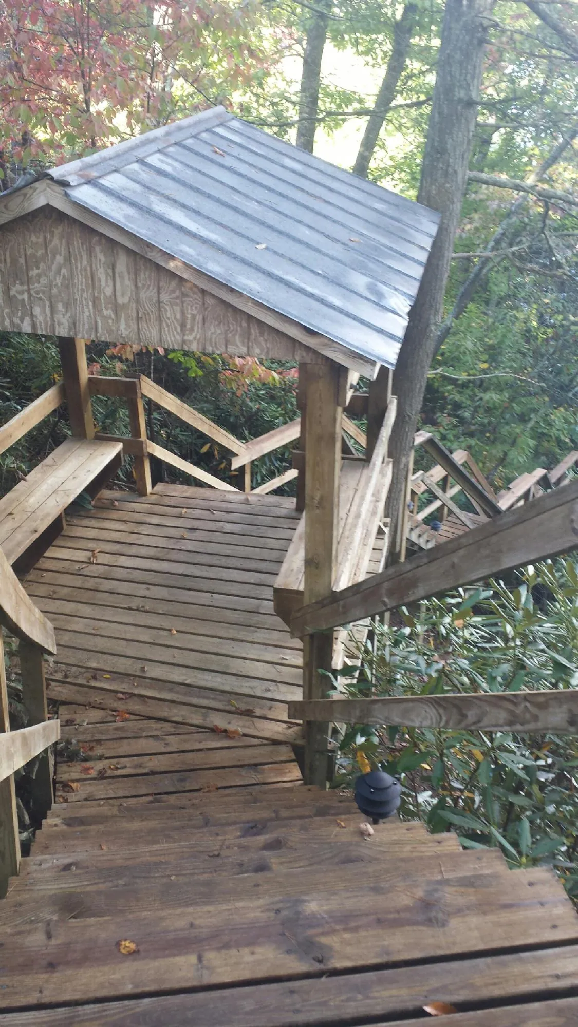 Metal roofed shelter over wooden steps on a wooded walkway — Skylight Repair & Installation work by our crew in Mifflinburg