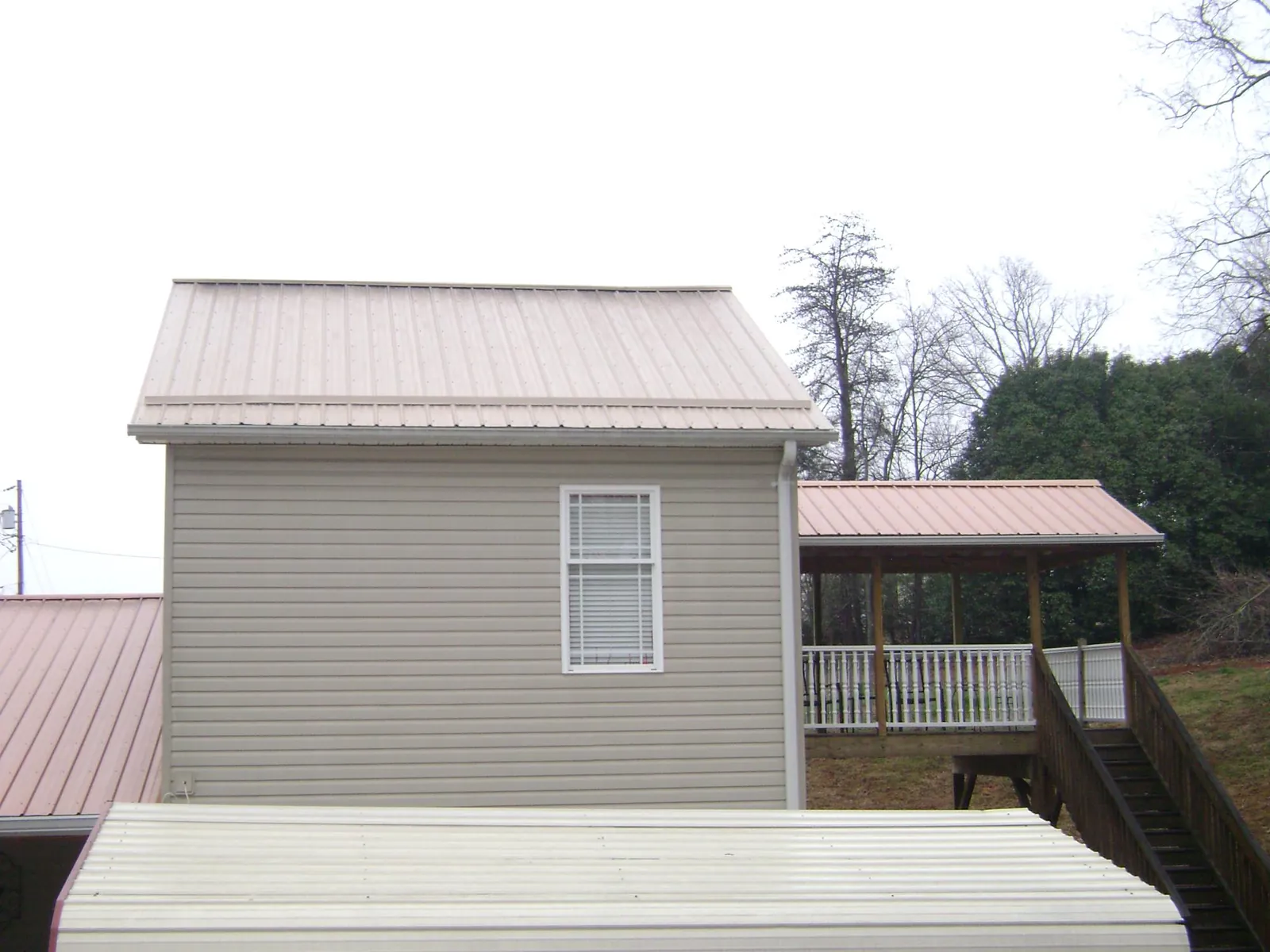 Tan metal roofs on a two story addition and attached porch, from a Roof Replacement job in Mifflinburg