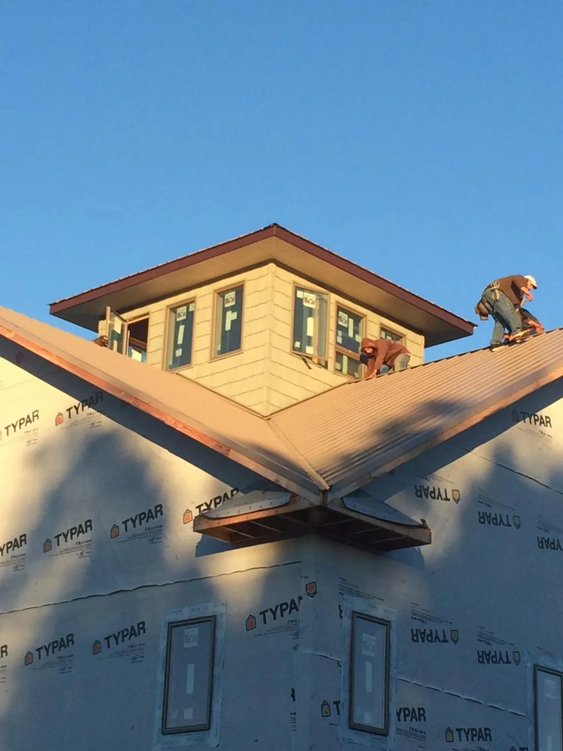 Roofers working around a rooftop cupola on a new metal roof at sunset — Roof Waterproofing in Mifflinburg by Roofing Brothers